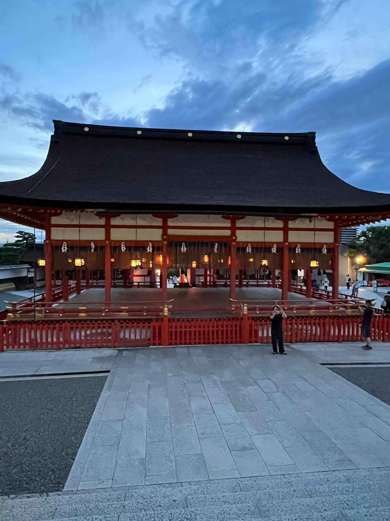 Fushimi Inari main shrine hall at dusk with glowing lanterns, Kyoto